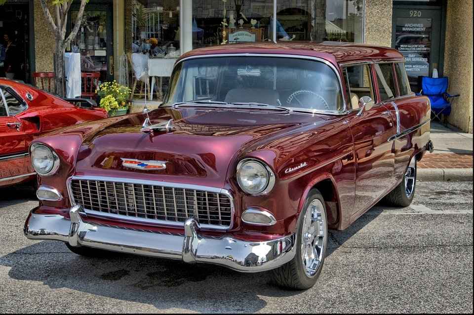 A classic 1955 Chevrolet station wagon in maroon color, parked on a street