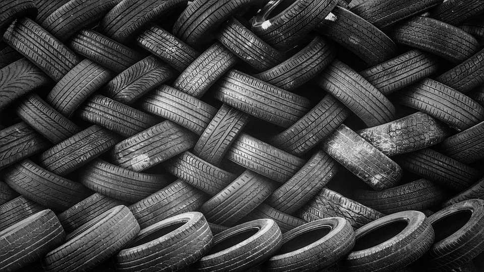 Stacked and intertwined used tires in a black-and-white pattern