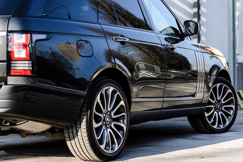 A shiny black SUV with large alloy wheels parked outdoors.